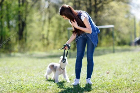 Hundetrainerin geht mit einem Hund an lockerer Leine über einen Weg in der Natur